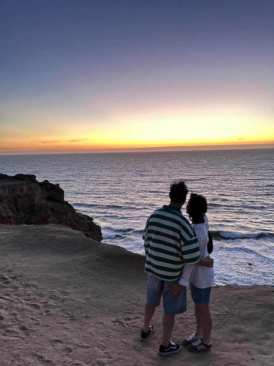 A man and woman standing on a cliff overlooking the ocean at sunset. — Timlaline / Timlalin dunes quad tour photo, Agadir Morocco