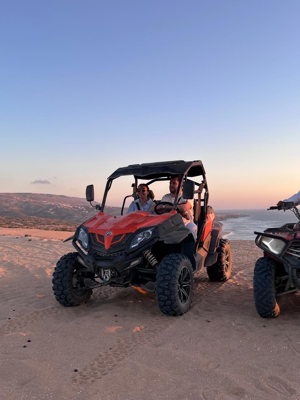 Buggy Tour at Timlaline at Timlaline dunes near Agadir, Morocco — A group of people riding in a red quad on a sandy beach.